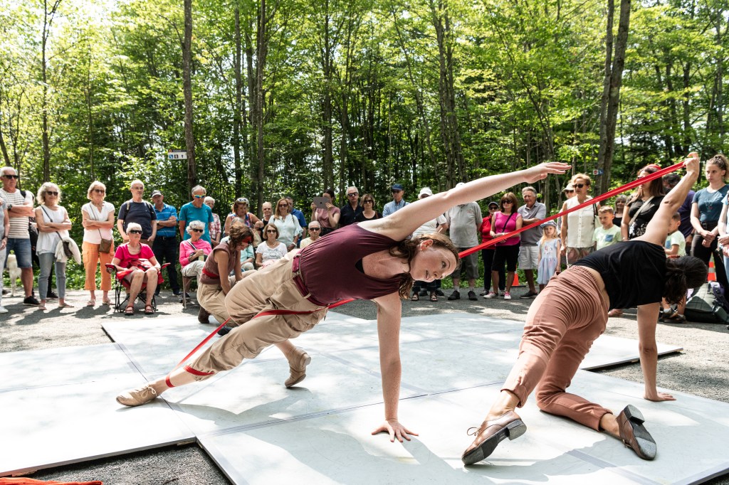 Performing Zeugma Danse's piece Aube, Chloe Hart reaches out her top arm in line with her body in a side plank. She is dressed in a maroon camisole and khaki pants.